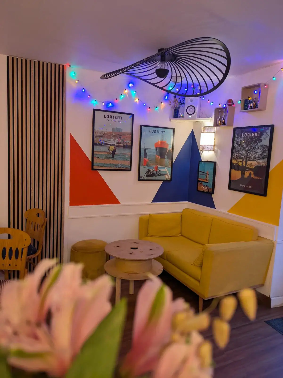 Le coin salon d’À Ton Aise à Lorient, canapé jaune, affiches de Lorient et guirlandes lumineuses