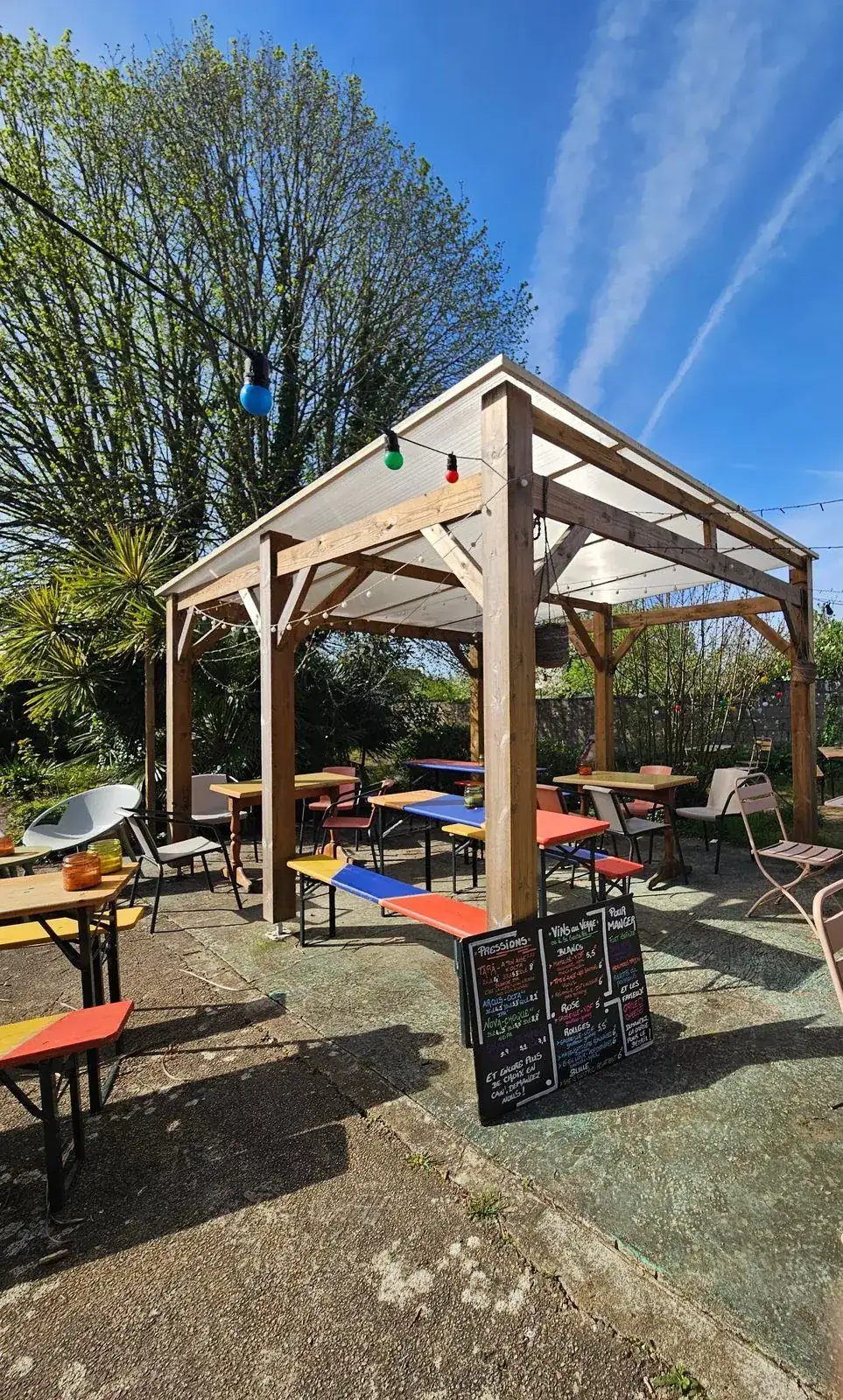 Le jardin d’À Ton Aise à Lorient, bancs de brasserie colorés et guirlandes
